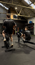 Two people using exercise bikes in a gym with 'Unleashed' branding.